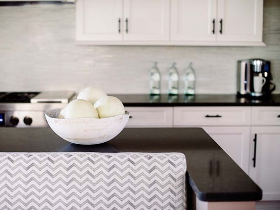 Aidan provided the cabinets in Alpine white and deep mushroom. The Caesarstone counters in piatra grey are from Marble X, and the rubbed bronze pulls are from the Lewis Dolin Collection. The honed tatami mosaic backsplash in paperwhite and cloud nine is from Architectural Ceramics. / Photo by Robert Radifera